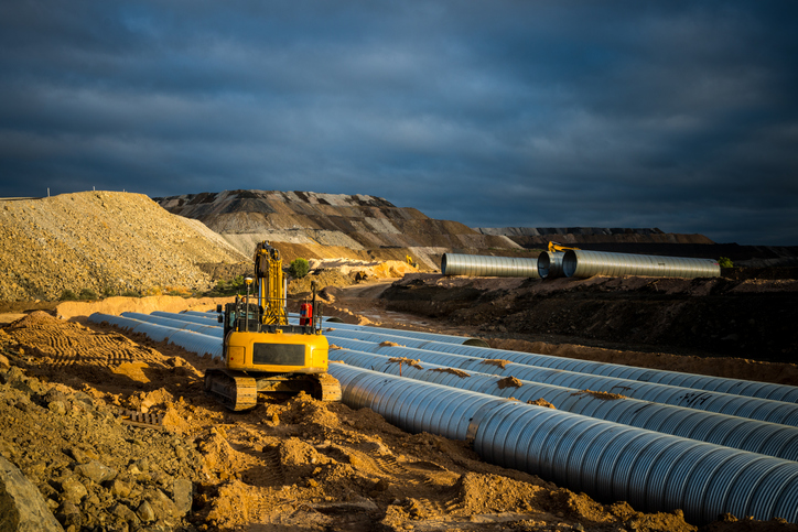 digger filling in culvert with steel pipes on mine